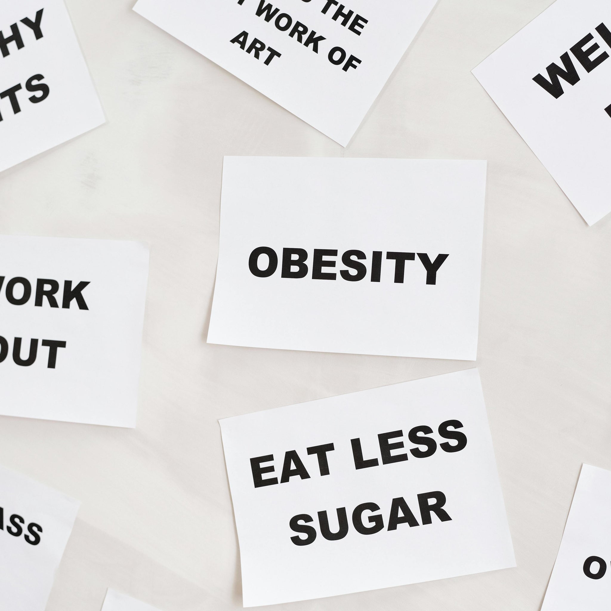 white paper cards with bold black text scattered on a light surface. The cards display health-related words and phrases