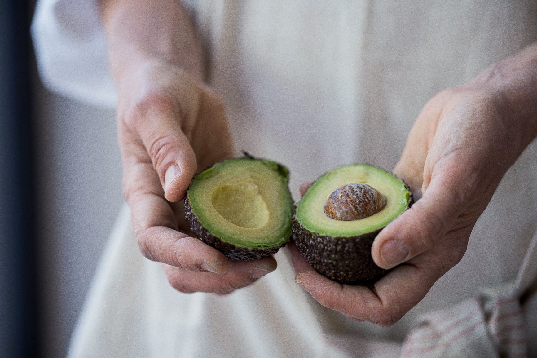 Close-up of two hands holding a freshly cut avocado