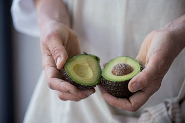Close-up of two hands holding a freshly cut avocado