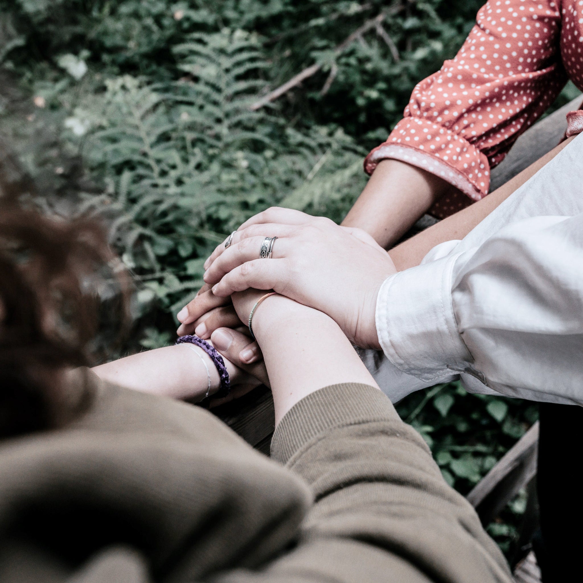 Three people stack their hands together in a gesture of support and unity
