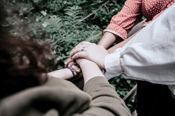 Three people stack their hands together in a gesture of support and unity
