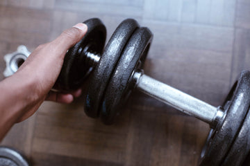 close up of a hand adding weight to a dumbbell
