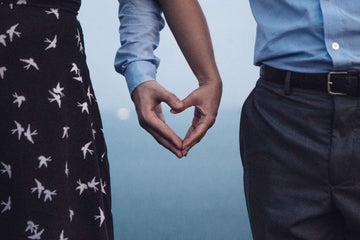 A couple holding hands in love heart shape