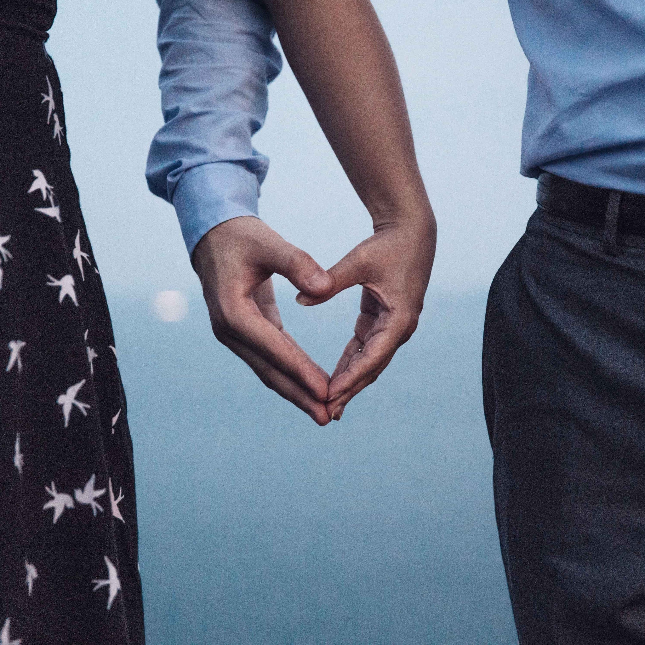 A couple holding hands in love heart shape