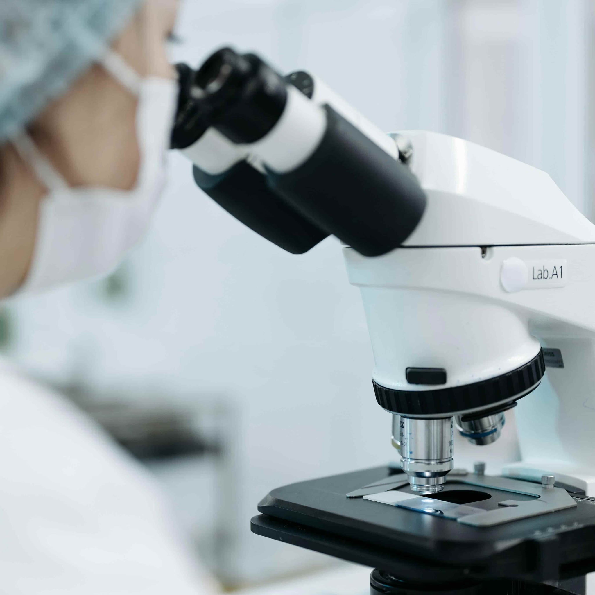 scientist looking through the eyepieces of a lmicroscope