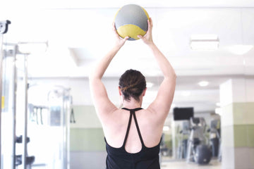 woman lifting fitness ball